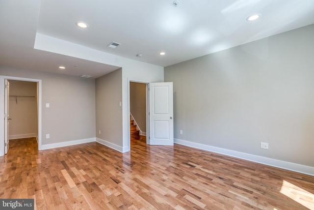 unfurnished bedroom with visible vents, a walk in closet, light wood-style flooring, recessed lighting, and baseboards