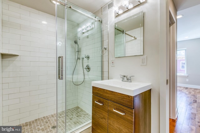 bathroom with visible vents, a stall shower, wood finished floors, baseboards, and vanity