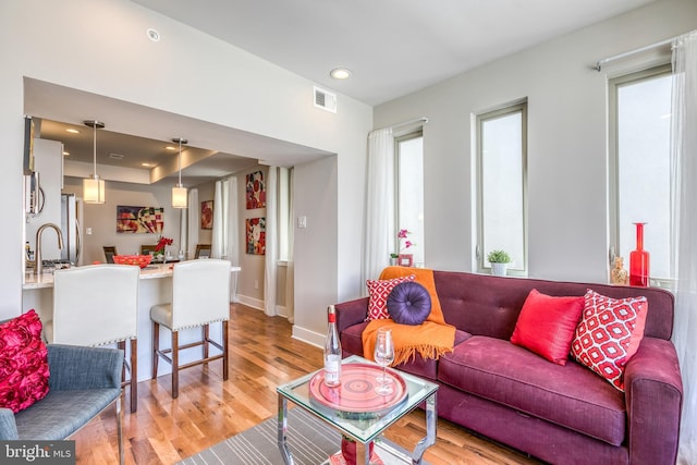 living room with visible vents, recessed lighting, light wood-type flooring, and baseboards