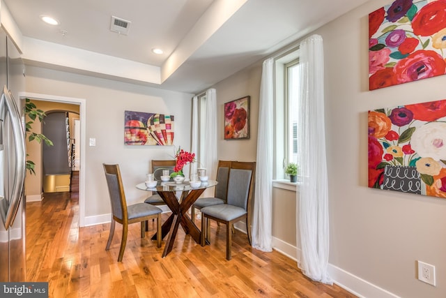 dining area featuring visible vents, light wood-style flooring, recessed lighting, arched walkways, and baseboards