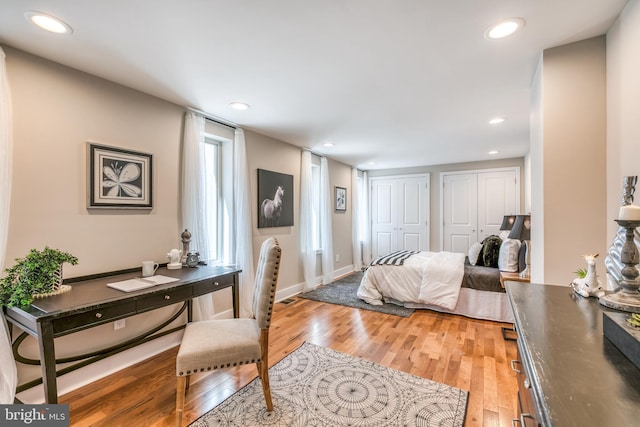 bedroom with recessed lighting, light wood-style flooring, and multiple closets