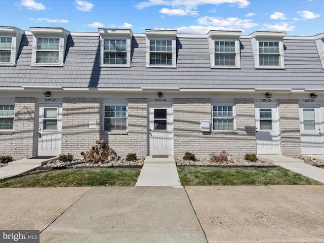 townhome / multi-family property featuring mansard roof and brick siding