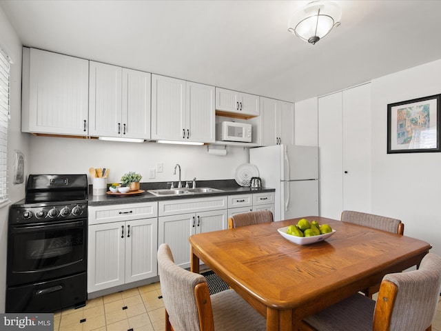 kitchen featuring white appliances, light tile patterned flooring, a sink, white cabinetry, and dark countertops