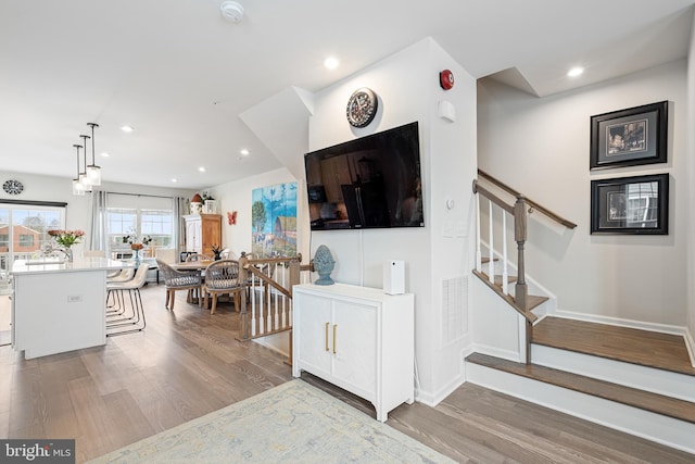 living area with recessed lighting, visible vents, wood finished floors, and stairs