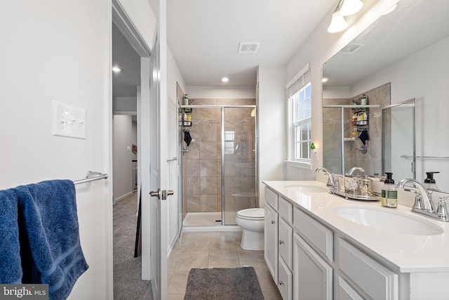 bathroom with double vanity, a shower stall, and a sink