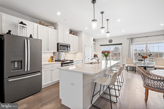 kitchen with white cabinets, wood finished floors, appliances with stainless steel finishes, and a sink