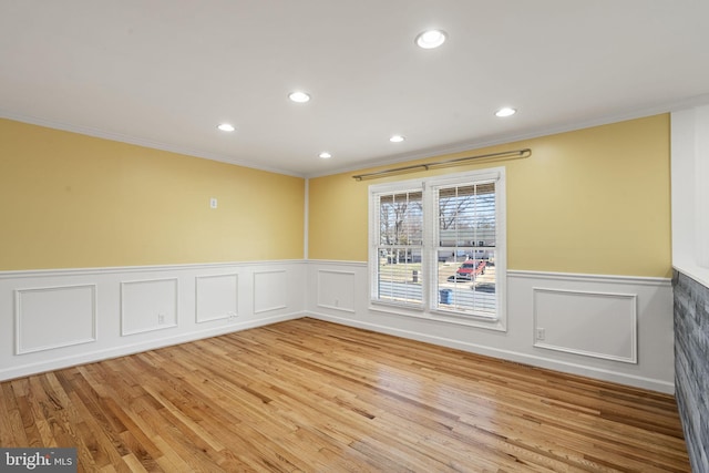 empty room with recessed lighting, light wood-style floors, and a wainscoted wall