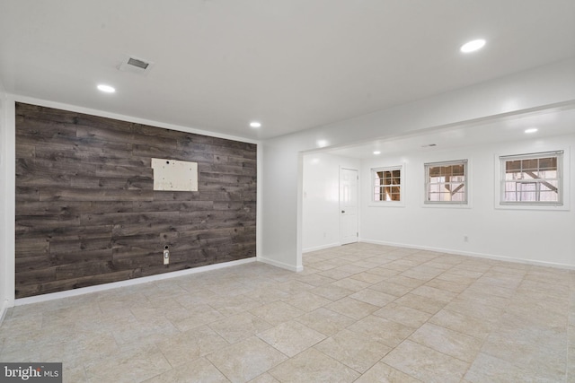 basement with recessed lighting, wood walls, an accent wall, and visible vents