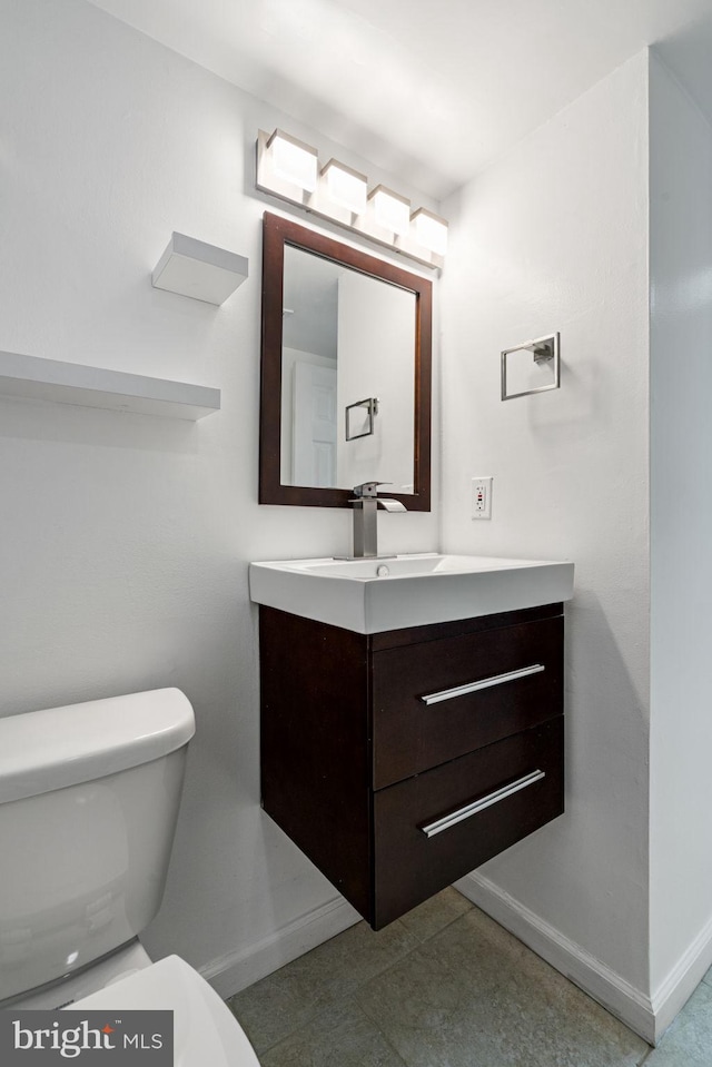 half bath with toilet, vanity, and baseboards