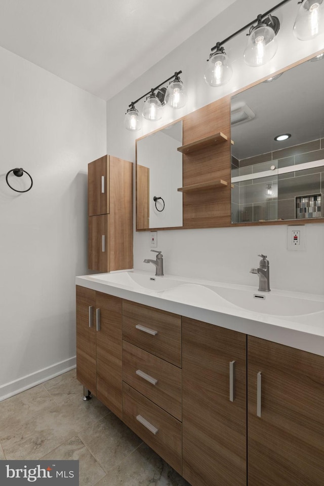 bathroom with double vanity, baseboards, a shower stall, and a sink