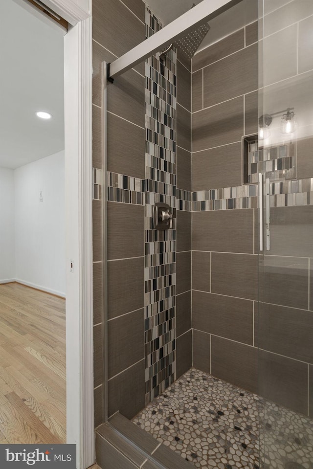 bathroom featuring wood finished floors and a stall shower