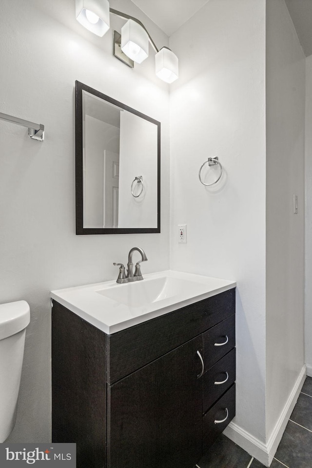 bathroom featuring vanity, toilet, baseboards, and tile patterned flooring