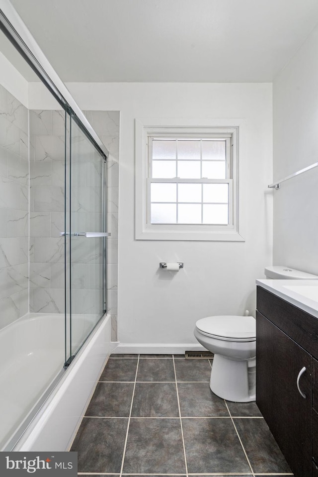 bathroom featuring baseboards, toilet, tile patterned floors, combined bath / shower with glass door, and vanity