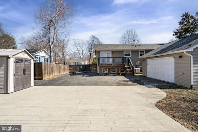 back of house with a storage unit, driveway, fence, an outdoor structure, and a garage