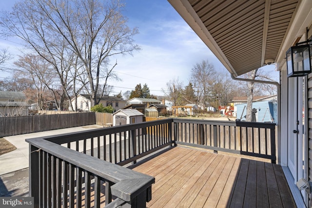 deck with a fenced backyard, a residential view, a storage shed, and an outdoor structure