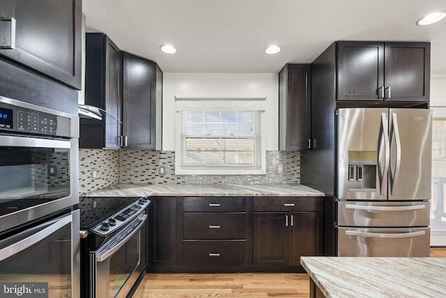 kitchen featuring light stone counters, recessed lighting, stainless steel appliances, tasteful backsplash, and light wood-type flooring