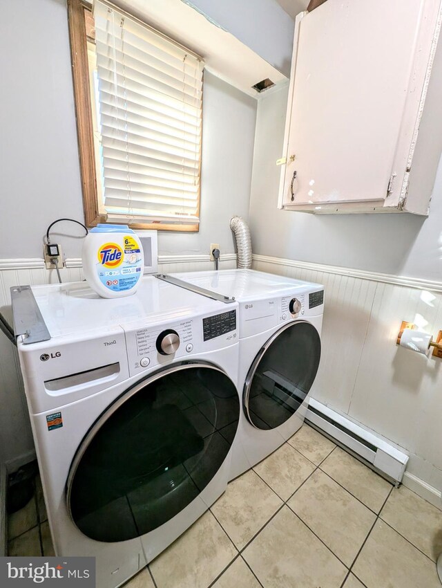 laundry room featuring a baseboard heating unit, wainscoting, washer and dryer, light tile patterned flooring, and cabinet space