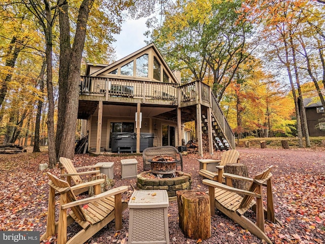 rear view of property featuring a wooden deck, stairway, a fire pit, and a hot tub