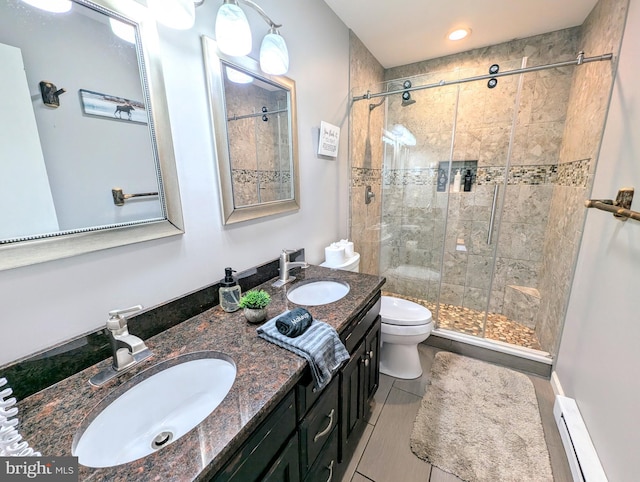 full bathroom featuring a sink, a shower stall, double vanity, and a baseboard radiator