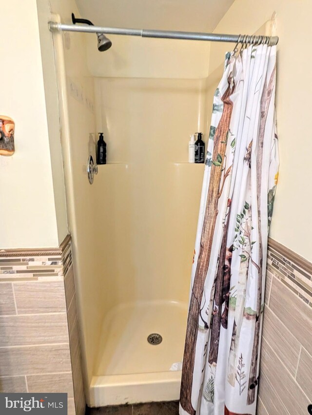 bathroom featuring tile walls, wainscoting, and a shower stall