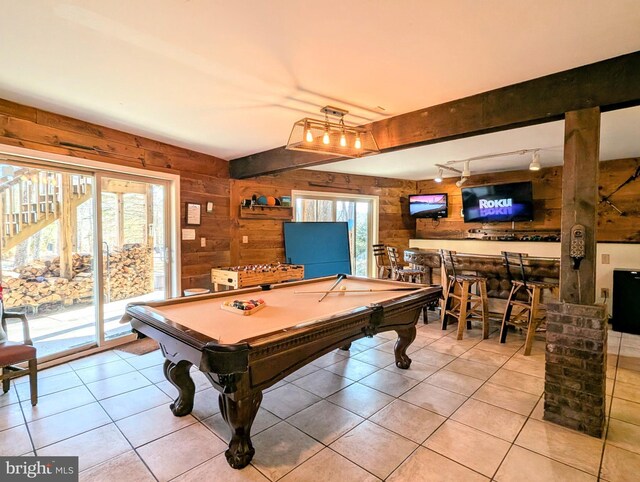 recreation room featuring light tile patterned floors, a healthy amount of sunlight, and wood walls