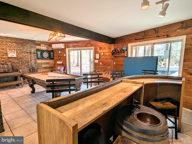 game room with a wealth of natural light, beam ceiling, wood walls, and a wall unit AC