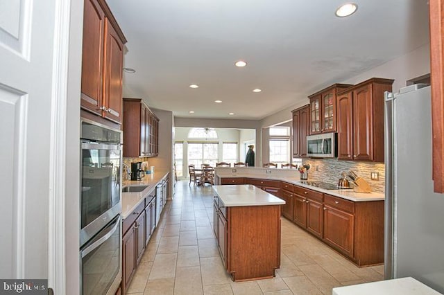 kitchen featuring recessed lighting, stainless steel appliances, light countertops, glass insert cabinets, and backsplash