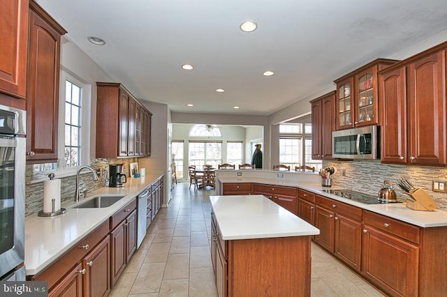 kitchen with glass insert cabinets, light countertops, a peninsula, stainless steel appliances, and a sink