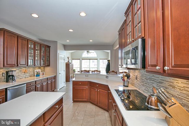 kitchen with ceiling fan, light countertops, glass insert cabinets, and stainless steel appliances