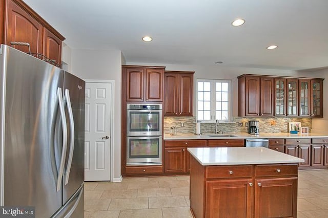 kitchen with tasteful backsplash, appliances with stainless steel finishes, light countertops, and a sink