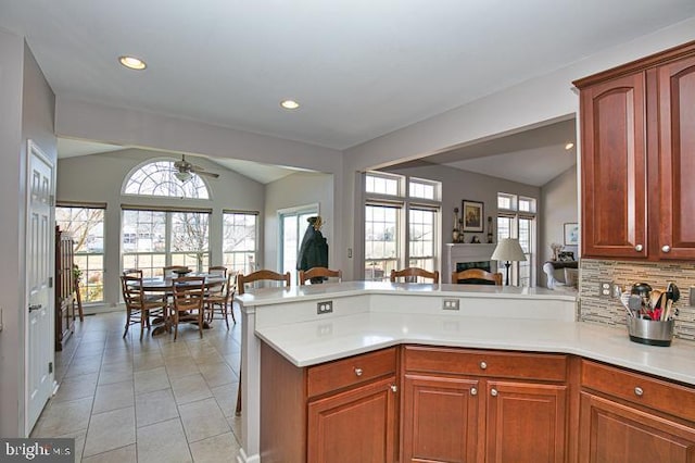 kitchen featuring decorative backsplash, a peninsula, light countertops, and lofted ceiling