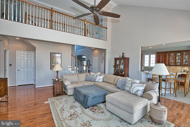 living area featuring stairs, wood finished floors, baseboards, and a ceiling fan