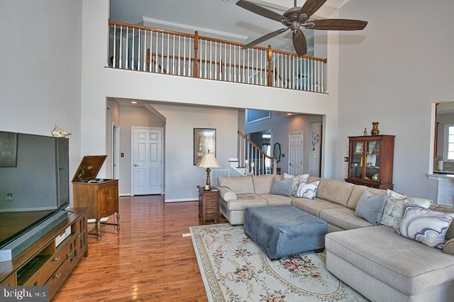 living area with stairs, wood finished floors, baseboards, and ceiling fan