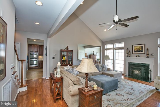 living area featuring a high end fireplace, stairs, recessed lighting, wood finished floors, and high vaulted ceiling