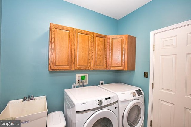 clothes washing area with a sink, cabinet space, and separate washer and dryer