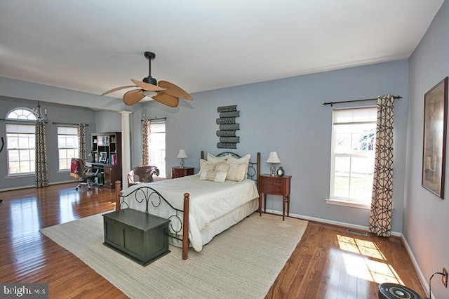 bedroom with baseboards, multiple windows, visible vents, and wood finished floors