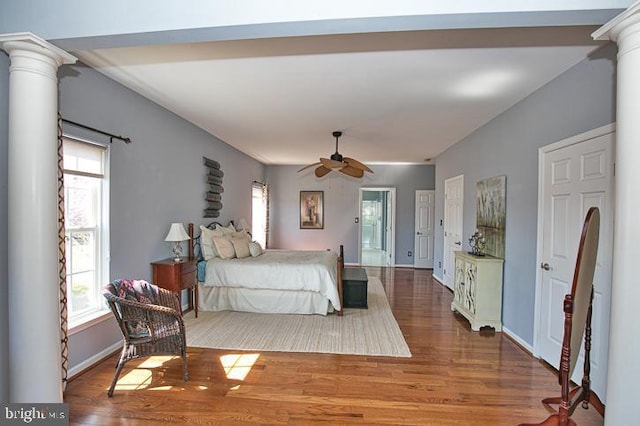 bedroom featuring decorative columns, baseboards, and wood finished floors