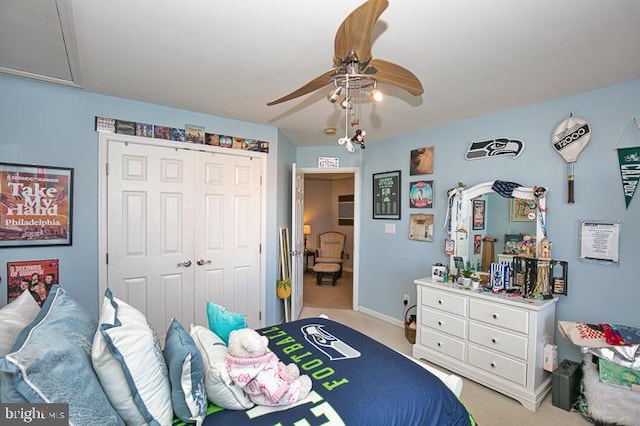 bedroom with a closet, light colored carpet, attic access, and a ceiling fan