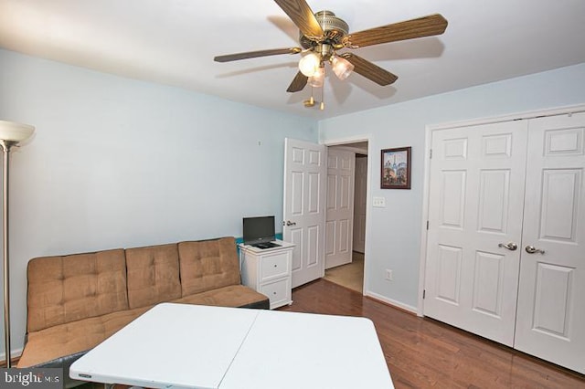 bedroom with a closet, baseboards, dark wood-type flooring, and ceiling fan