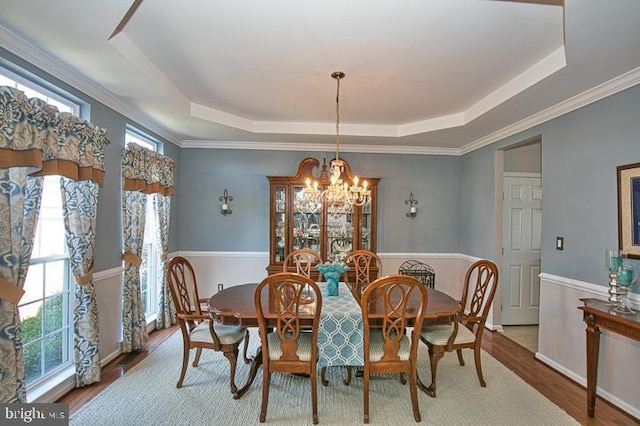 dining area with a raised ceiling, crown molding, wood finished floors, and a chandelier