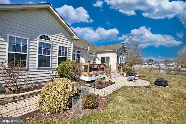 rear view of property with a yard, a deck, and a patio area