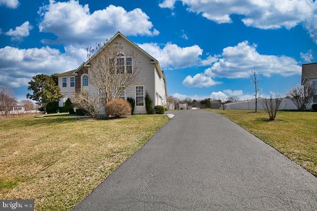 view of side of property with aphalt driveway and a lawn