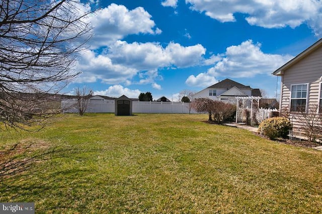 view of yard featuring an outdoor structure, a fenced backyard, and a storage shed