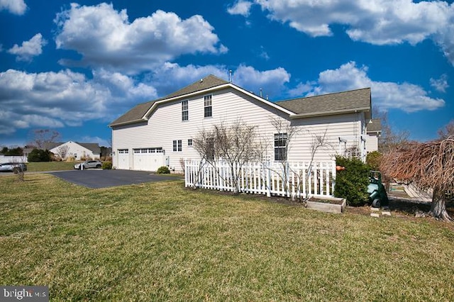 view of property exterior featuring aphalt driveway, a lawn, and a garage