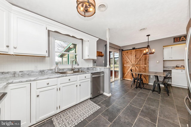 kitchen with a sink, a barn door, dishwasher, and white cabinets