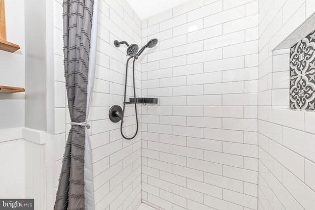 bathroom featuring a tile shower and wainscoting