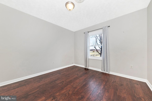 spare room with dark wood-style floors and baseboards