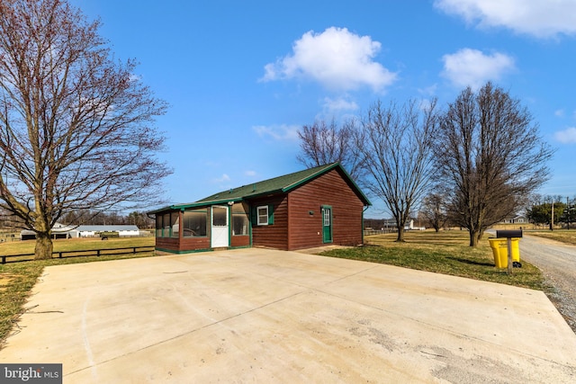 exterior space with a lawn, driveway, fence, and a sunroom