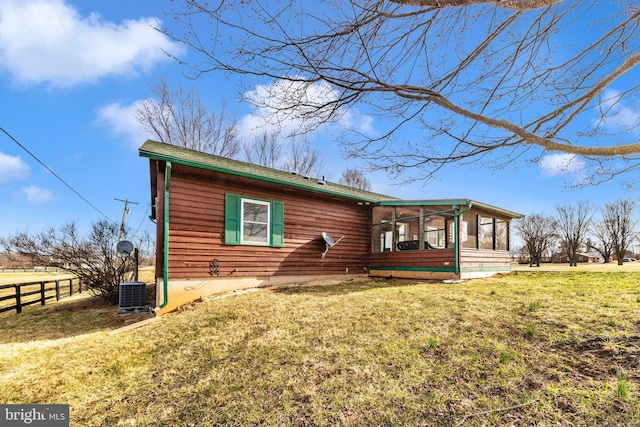 view of front of property with a front lawn, central air condition unit, fence, and a sunroom