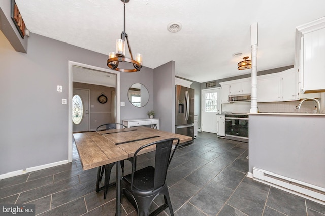 dining area featuring visible vents, baseboards, stone finish flooring, a baseboard heating unit, and a notable chandelier